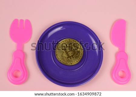 A metal bitcoin coin lies in a plastic plate