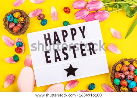 Stylish background with colorful easter eggs isolated on yellow background with pink tulip flowers. Flat lay, top view, mockup, overhead, template