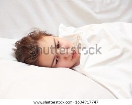 sick girl lying in white bed with a thermometer in mouth. coronavirus