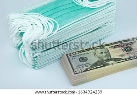 Price gouging during shortage of virus masks. High price of masks and demand during quarantine in United States, Europe and global pandemic. Pile of anti virus surgical face masks and money. Concept. Royalty-Free Stock Photo #1634924239