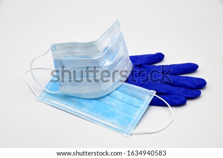 Protective face mask for protection against germs in the mouth and nose. Blue protective glove under the masks. Protection for corona virus Royalty-Free Stock Photo #1634940583