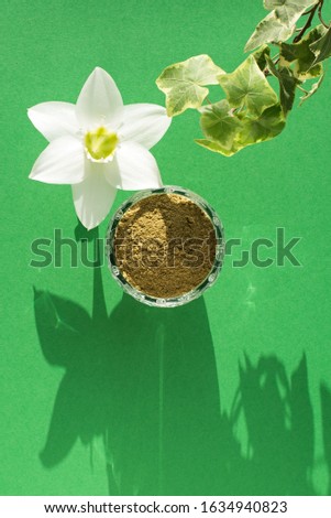 natural henna powder, white flower and plant loach on a green background, vertical. Concept female beauty and cosmetology. Eyebrow and hair coloring.