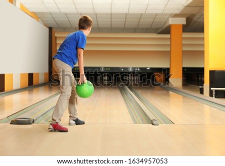 Preteen boy throwing ball at bowling club. Space for text
