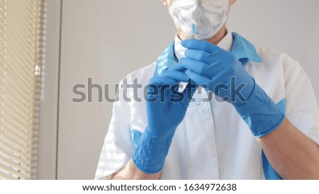 Doctor with syringe, man in medical mask and blue gloves preparing to injection. Concept of vaccination and treatment in clinic