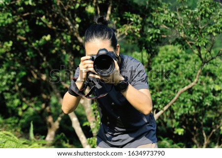 Photographer taking photo in the forest with digital camera