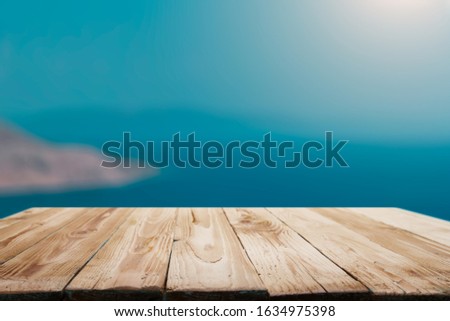 Wooden empty surface on defocused blue sea background in afternoon.