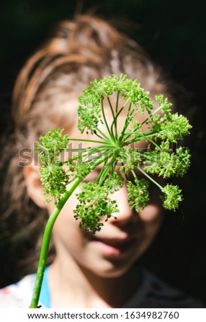Portrait of a girl covering her face with a green flower
