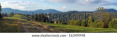 Mountain evening panorama view with earth road, haystacks and country estate (Slavske village outskirts, Carpathian Mts, Ukraine). Nine shots composite picture.