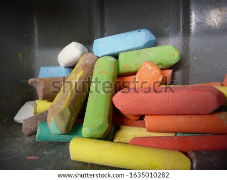 colorful pieces of chalk lie in a gray container