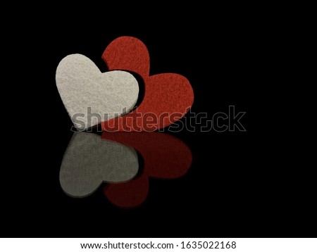 The inscription "Love" and a red heart on a black background. Reflection of two hearts from a glossy surface. The concept of Valentine's Day, wedding, birthday and other holidays.