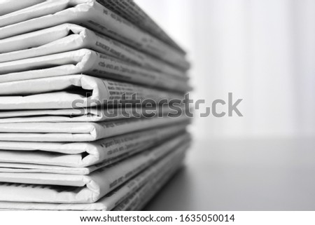 Stack of newspapers on grey table, space for text. Journalist's work