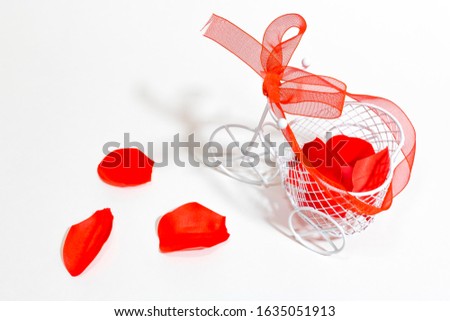 Miniature white Bicycle decorated with red ribbon and red flowers on a white background. Wedding