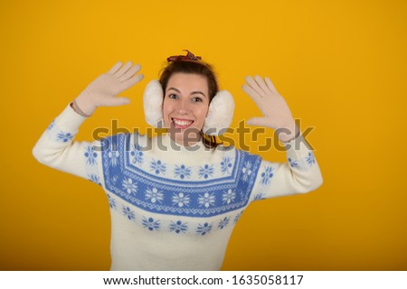 pretty smiling woman shows palm in gloves on a yellow background