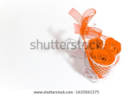 White miniature Bicycle decorated with orange ribbon and flowers on a white background. Wedding
