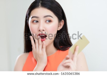 Picture showing smart attractive young asian girl holding credit card with happiness and joyful. Online shopping payment and e-commerce concept.