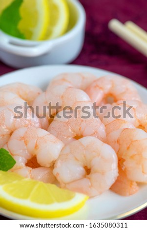 succulent fresh cooked whole king prawns peeled  with lemon and mint on a dish  blurred background for copy space 