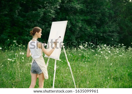 young woman draws a picture on canvas an easel on the street