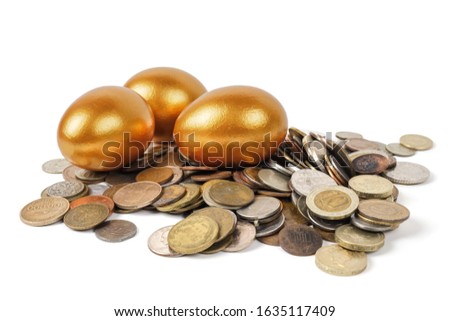 Golden Easter eggs on a bunch of coins on a white background