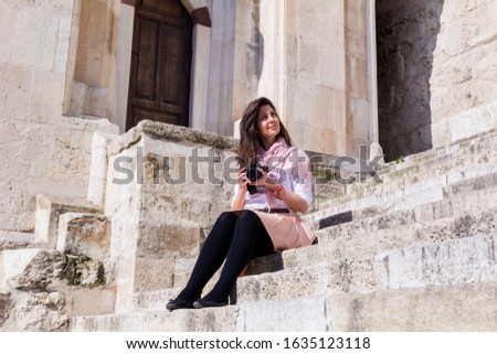 Woman Sitting on Stairs with Photo Camera in the Hands ..Photographer in the City 