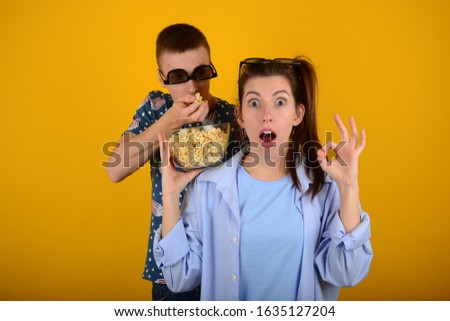 surprised woman man in 3d glasses eating popcorn on a yellow background