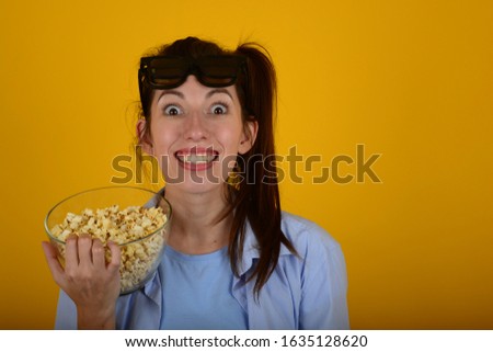 woman with popcorn smiling watching a movie on a yellow background portrait