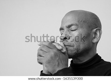 man praying to god with hands together on grey background stock photo