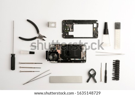 set tools workshop for mobiles, with broken open telephone, screwdrivers, cutter, glue, tweezers, magnifying glass, accessories red, pencil, white background.top view.concept mobile workshop