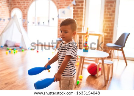 Beautiful toddler boy playing bowling at kindergarten