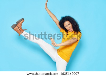 Cheerful beautiful woman curly hair yellow t-shirt blue background