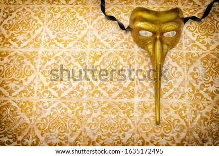 Venetian mask with a long nose over gold background