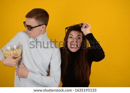 young couple watching a movie with popcorn in their hands advertising