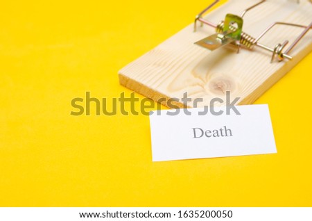 mousetrap with a piece of paper and the inscription Death on a yellow background with a copy space. concept or idea