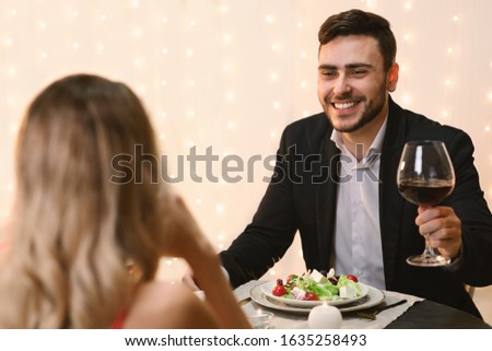 Handsome Man Making Toast For Love On Romantic Dinner With His Girlfriend in Restaurant, Celebrating Valentine's Day Together, Selective Focus