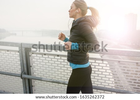 	
Blond hair female jogging outdoors on cold winter day.	
