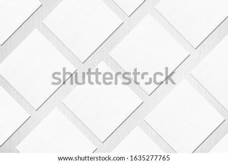 Many empty white square business card mockups with soft shadows lying diagonally on neutral light grey textured background. Flat lay, top view. Open composition.