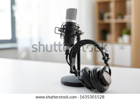 technology and audio equipment concept - headphones and microphone at home office or recording studio