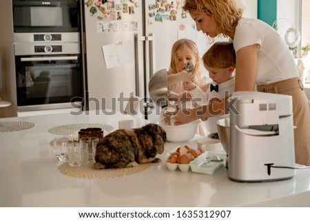 happy family  preparing for Easter holiday. Mom with children in the kitchen bakes cakes and paints eggs. Domestic rabbits