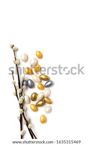Easter gold, white and silver chocolate eggs with willow isolated on white. Vertical frame for text, blank for logo and place for text. Top view, flat lay, festive picture for design