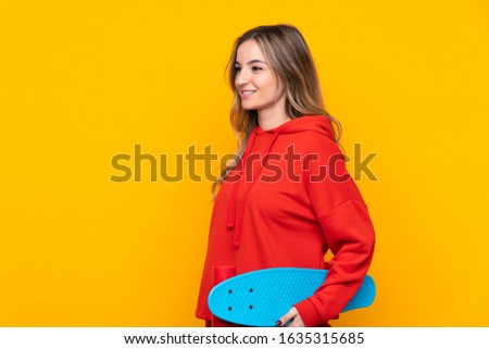 Young woman over isolated yellow background with a skate