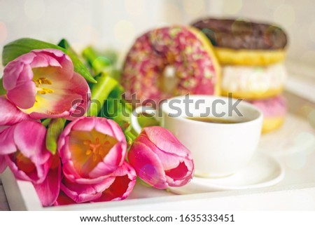 Breakfast with flowers and coffee. Greeting card with a festive breakfast of a cup of coffee, donuts and pink tulips. Greeting card for the holiday of March 8, mother's day, birthday