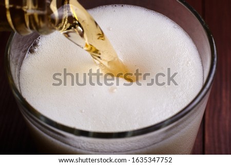 Pouring beer with foam into a glass.