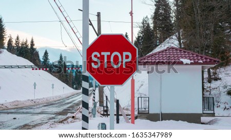 Stop sign on the road, giving information to stop and give way. Winter and snowy background. Train tracks on the background