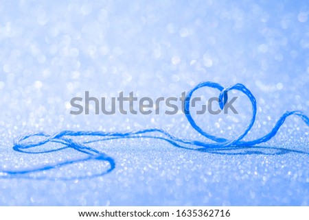 Blue thread in the shape of a symbol of love of heart on a blurry background for Valentine's day
