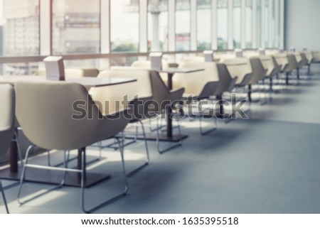 Defocused and blurred image of table and chair in food court or food center indoor plaza. Ready for client and tourist to sitting and eating. For background about tourism and food Business etc.