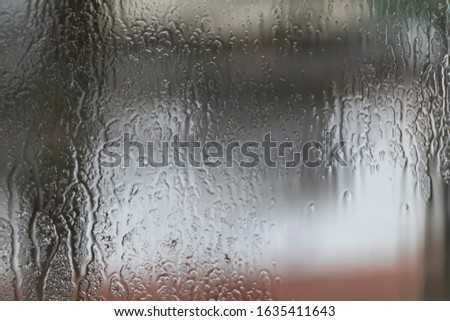 Rainy weather, raindrops on the glass of window, water drips wet. Texture or a background.