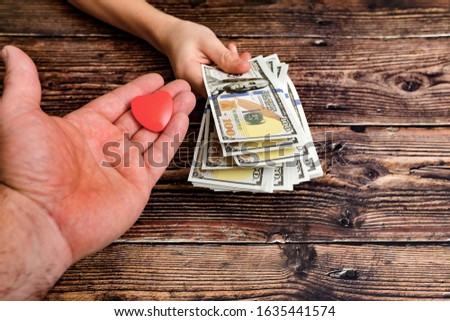 A man holds out his hand with a heart in exchange for dollars, the concept of selling love for money