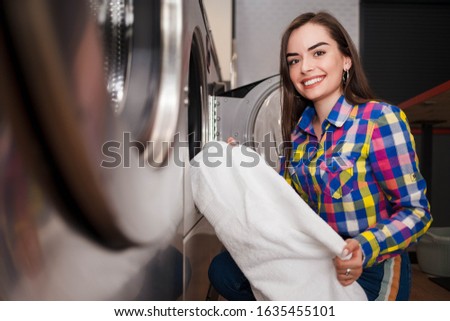Girl loads laundry into a washing machine. woman in laundrette Royalty-Free Stock Photo #1635455101