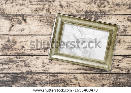 Photo frame with a paper sheet on a wooden table