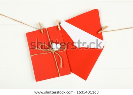 Paper envelopes with heart hanging on white wooden background
