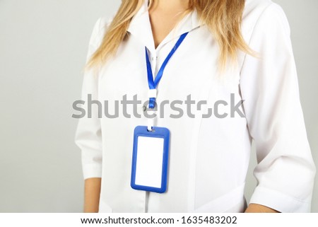 Businesswoman with blank bagde on grey background
